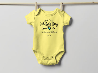 Yellow baby onesie with "Our First Mother's Day" text and a heart.