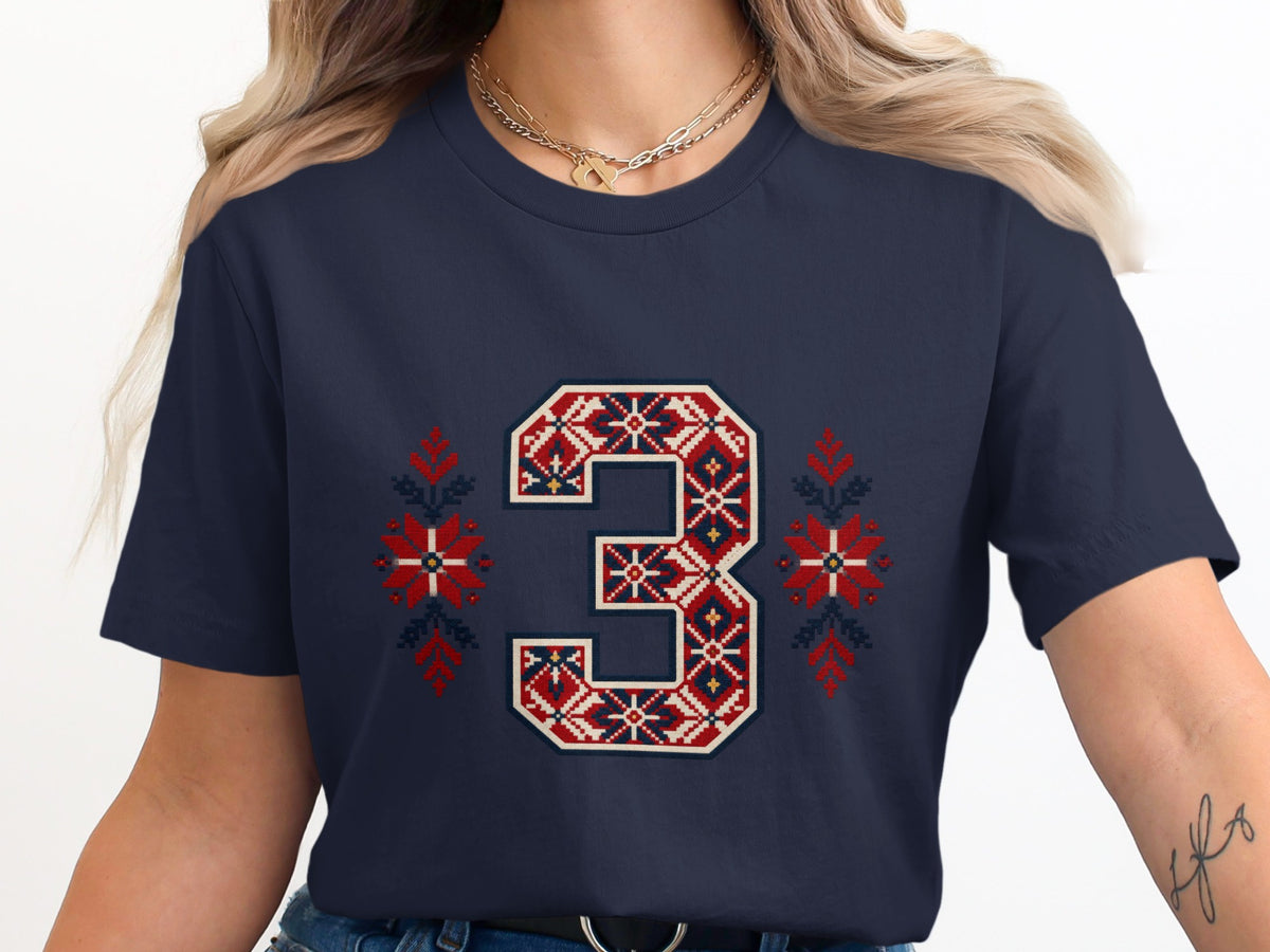 A dark blue t-shirt featuring a large varsity number three with a red and white Nordic pattern.