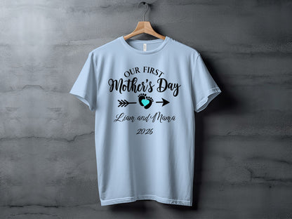 Light blue t-shirt with "Our First Mother's Day" text and heart arrow design.