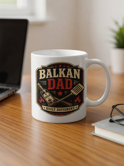 Mug with "BALKAN DAD BUILT DIFFERENT" text, a bottle, and a spatula.