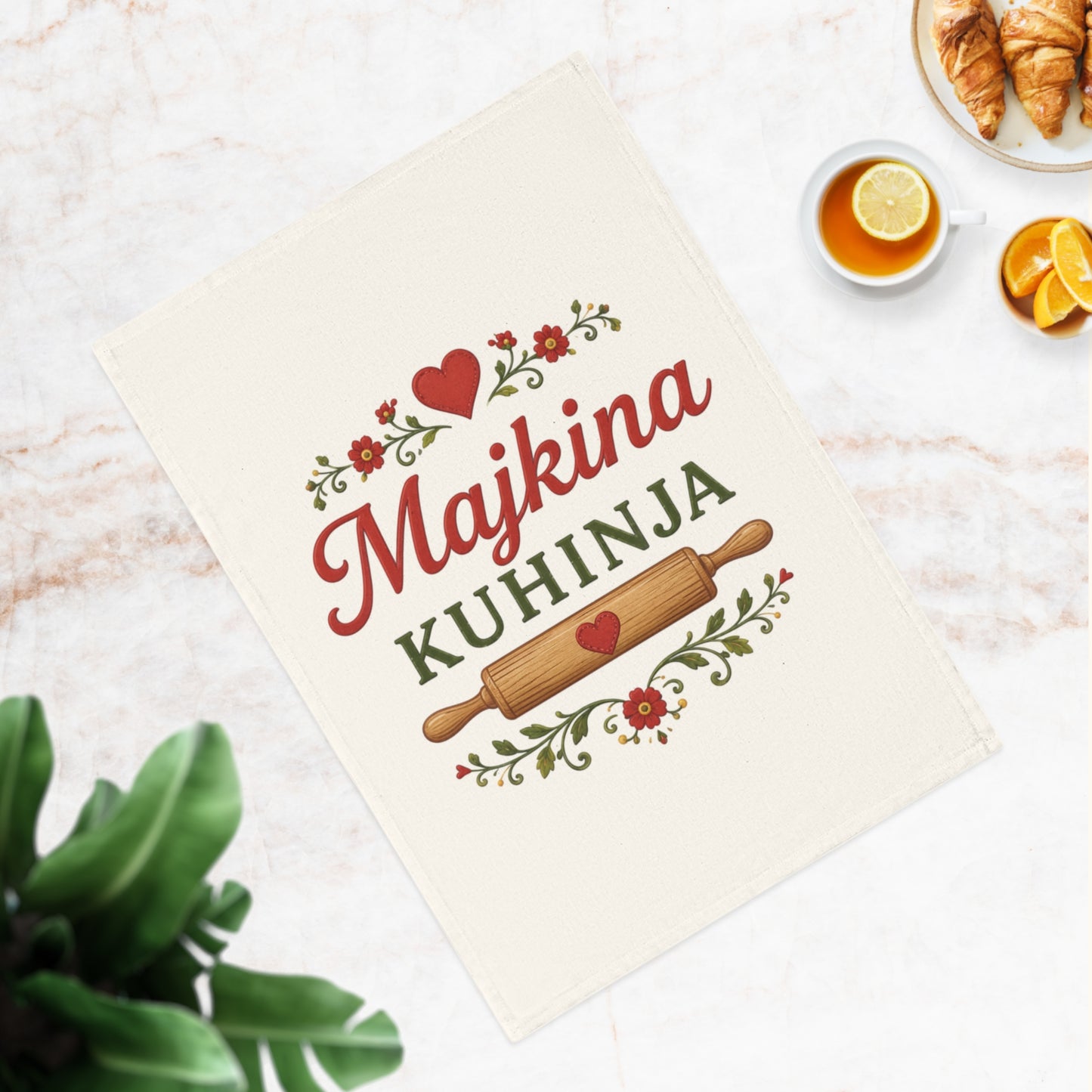 Decorative tea towel with "Majkina KUHINJA" text, rolling pin, and floral accents.