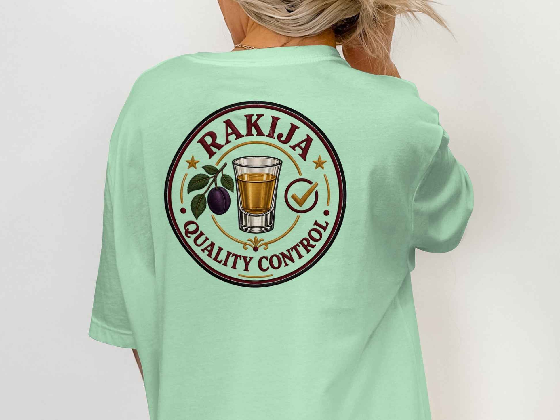Rakija Quality Control circular logo with shot glass and plum on mint t-shirt.