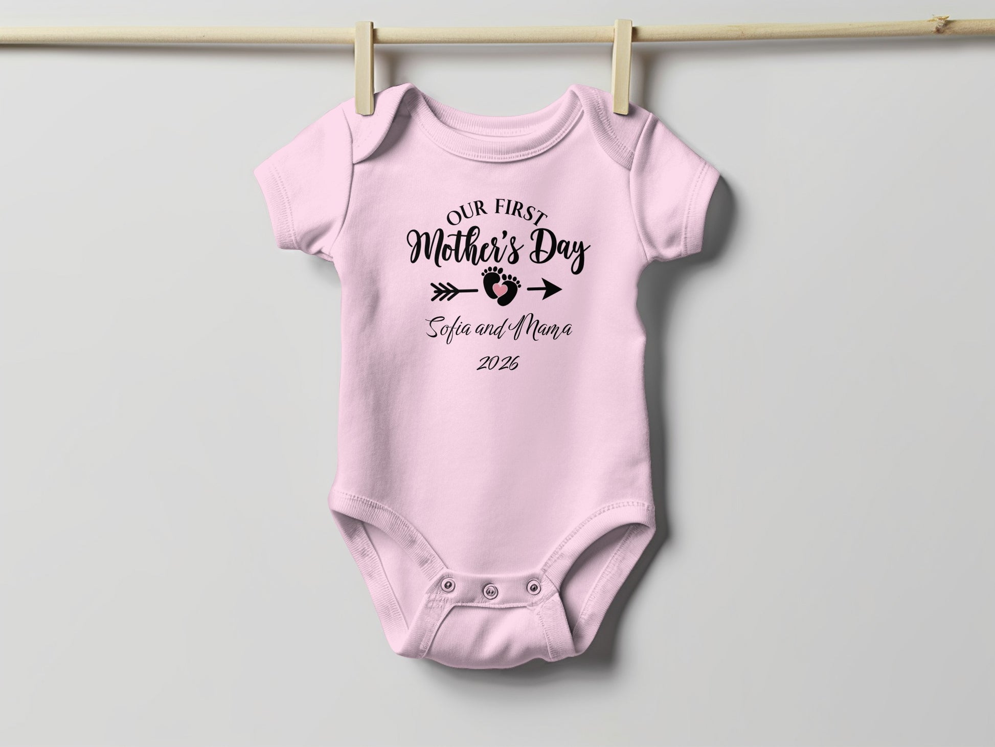 Pink baby onesie with "Our First Mother's Day Sofia and Mama 2026" text.
