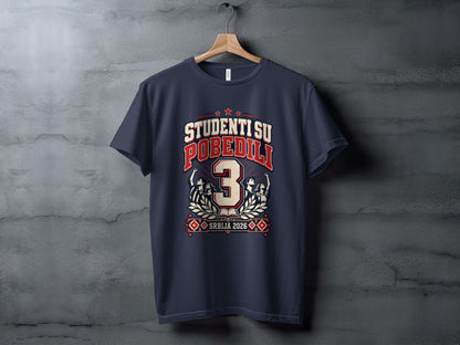 A dark gray t-shirt hanging on a wooden hanger, featuring a red and white graphic with the text "STUDENTI SU POBEDILI" and "SRBIJA 2026."