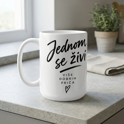 White mug with black script text "Jednom se živi" and "Više dobrih priča" with heart.