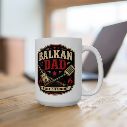 White mug with "BALKAN DAD BUILT DIFFERENT" text and grilling utensils.